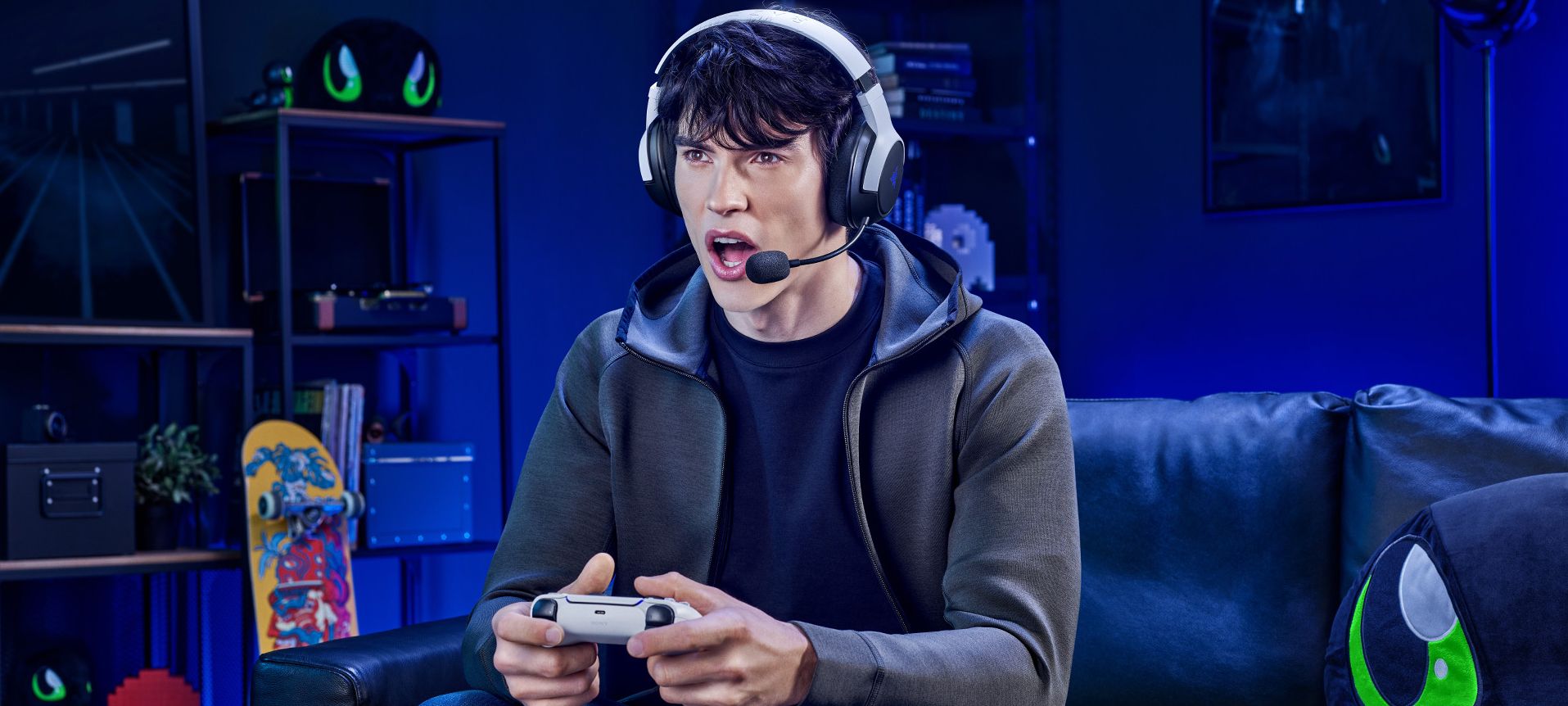 presentación de los audifonos razer kaira para playstation. En la imagen una persona sentada en silla razer disfruando un videojuego con sus audifonos razer